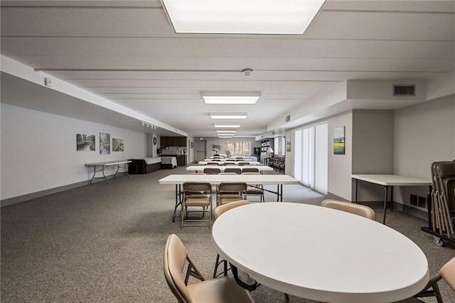 dining area featuring dark carpet, visible vents, and baseboards