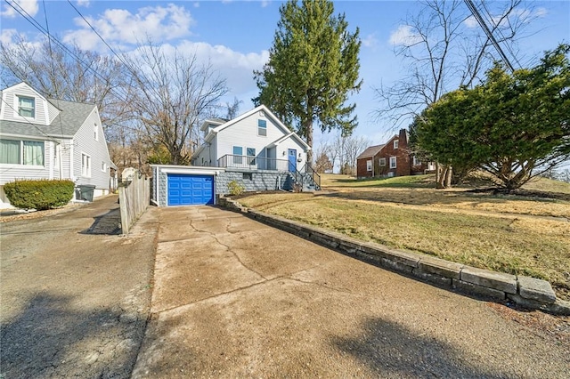 view of front of house featuring stairs, a residential view, concrete driveway, and a front yard