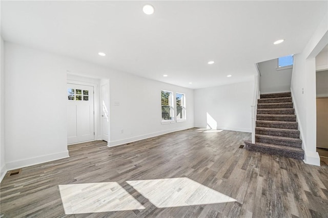 unfurnished living room with stairs, recessed lighting, baseboards, and wood finished floors