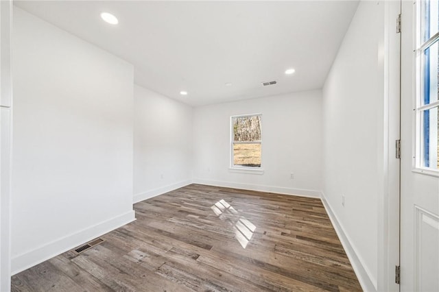 unfurnished room with wood finished floors, visible vents, and baseboards