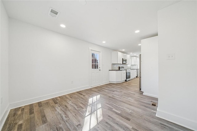 unfurnished living room featuring light wood finished floors, baseboards, visible vents, and recessed lighting