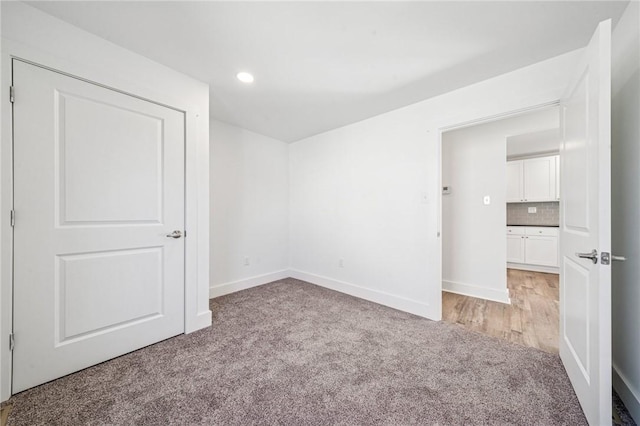 unfurnished bedroom featuring baseboards, recessed lighting, and light colored carpet