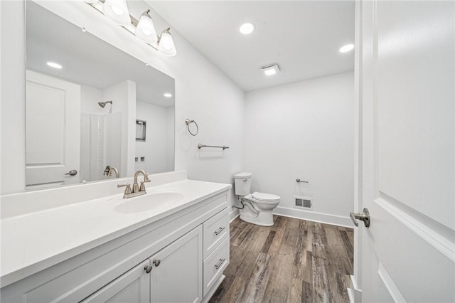 bathroom with toilet, recessed lighting, wood finished floors, vanity, and visible vents