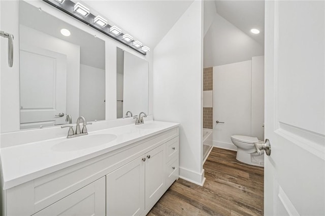 bathroom with double vanity, a sink, toilet, and wood finished floors