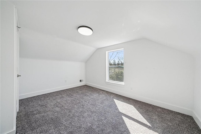 bonus room with lofted ceiling, dark colored carpet, visible vents, and baseboards