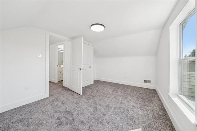 additional living space with lofted ceiling, baseboards, visible vents, and light colored carpet