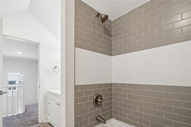 bathroom with vaulted ceiling, shower / bathing tub combination, and vanity