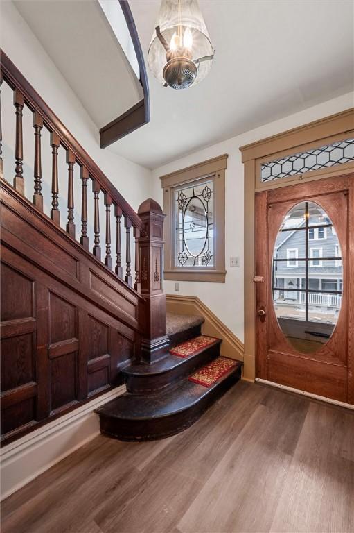 foyer entrance featuring stairway, an inviting chandelier, and wood finished floors