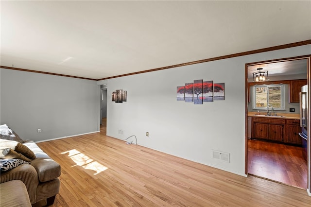 living area with light wood finished floors, baseboards, visible vents, and crown molding