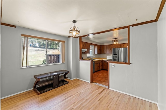 kitchen with light wood-style flooring, a sink, hanging light fixtures, stainless steel refrigerator with ice dispenser, and brown cabinets