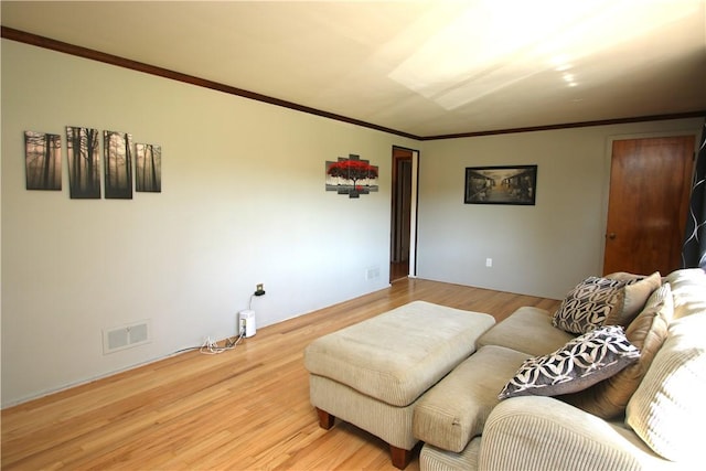 living area with ornamental molding, visible vents, and light wood finished floors