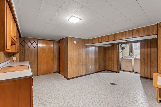 interior space featuring wood walls, light countertops, independent washer and dryer, light floors, and brown cabinetry