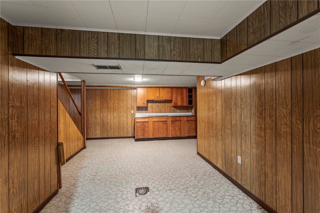 kitchen featuring brown cabinetry, light countertops, visible vents, and wooden walls