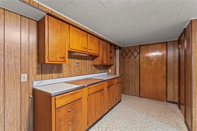 kitchen featuring wood walls, brown cabinetry, light countertops, and light floors