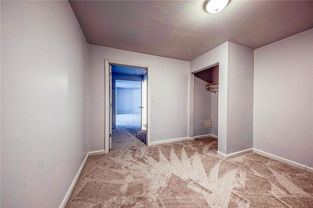 unfurnished bedroom featuring light carpet, a closet, and baseboards