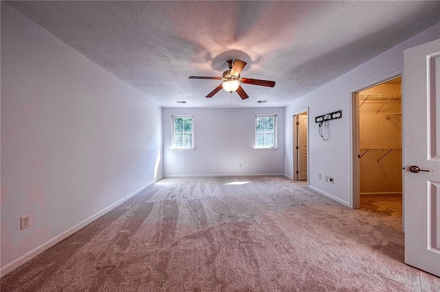 unfurnished room featuring a ceiling fan, light colored carpet, a textured ceiling, and baseboards