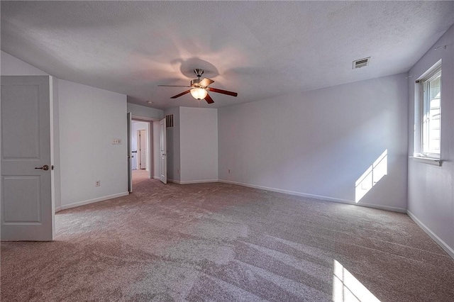 unfurnished room featuring baseboards, visible vents, light colored carpet, ceiling fan, and a textured ceiling