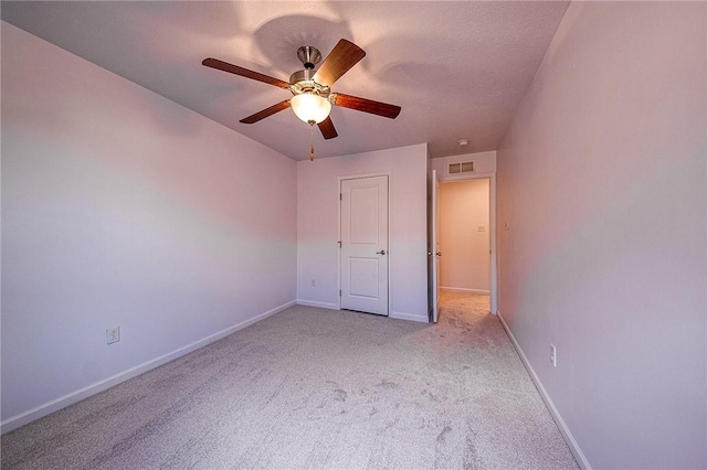 unfurnished bedroom featuring baseboards, visible vents, a ceiling fan, light colored carpet, and a textured ceiling