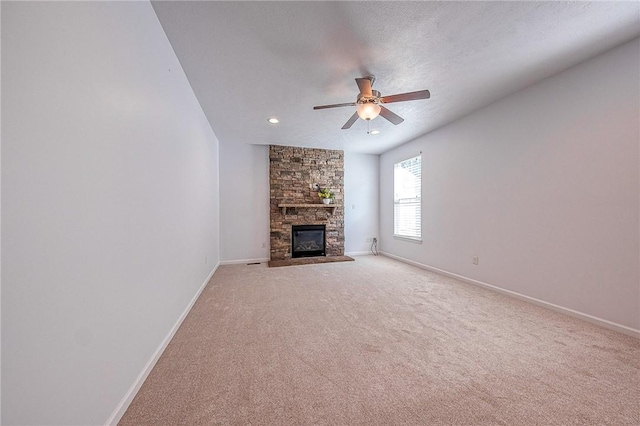 unfurnished living room with baseboards, light colored carpet, a textured ceiling, and a stone fireplace