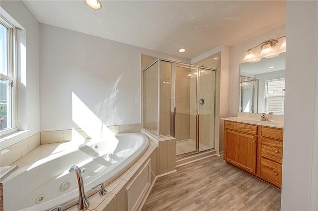 full bathroom featuring recessed lighting, wood finished floors, vanity, a shower stall, and a tub with jets