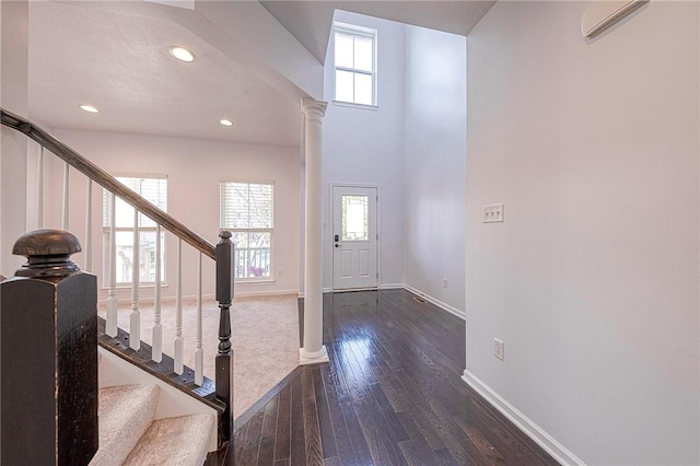 entryway with baseboards, dark wood-type flooring, a wealth of natural light, and ornate columns