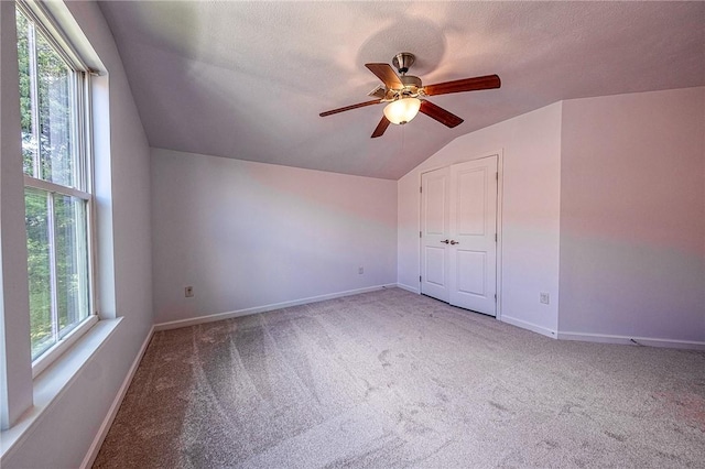 additional living space with vaulted ceiling, baseboards, carpet flooring, and a healthy amount of sunlight