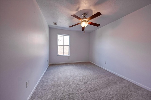 spare room with baseboards, visible vents, a ceiling fan, carpet, and a textured ceiling