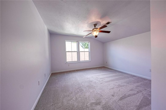 unfurnished room featuring lofted ceiling, ceiling fan, a textured ceiling, baseboards, and carpet