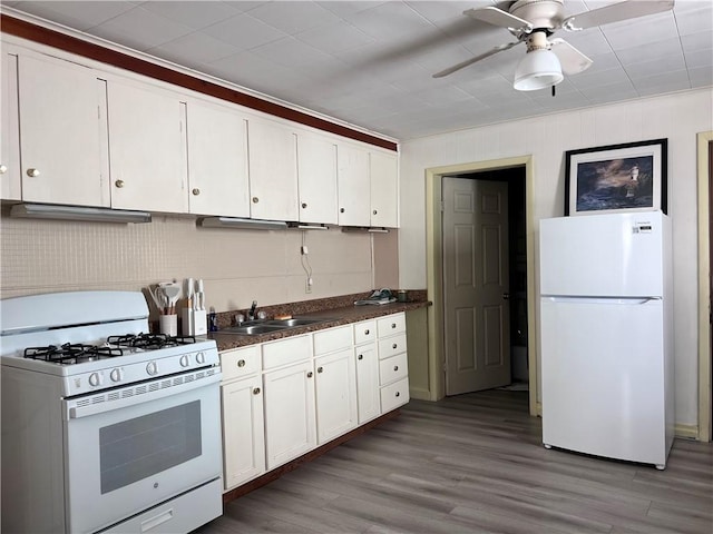 kitchen featuring white appliances, wood finished floors, a sink, white cabinetry, and dark countertops