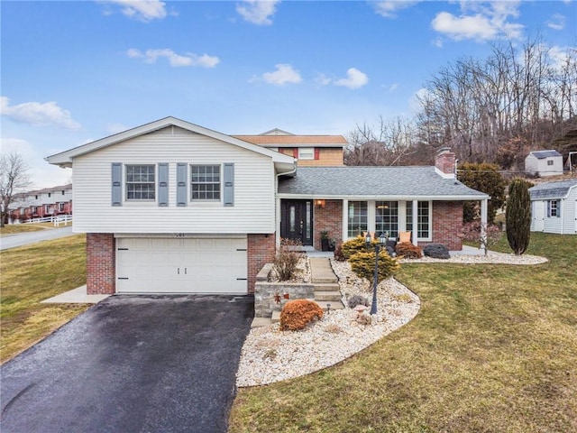 tri-level home with a garage, brick siding, driveway, a front lawn, and a chimney