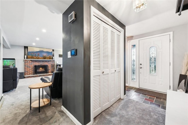 entryway with carpet, recessed lighting, a brick fireplace, stone finish floor, and baseboards