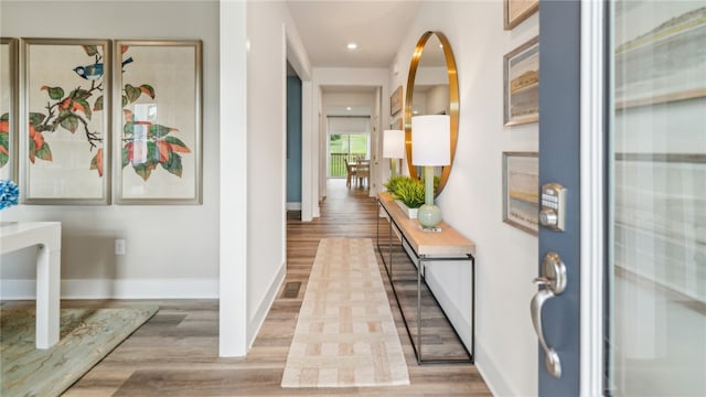 hall featuring light wood finished floors, baseboards, visible vents, and recessed lighting