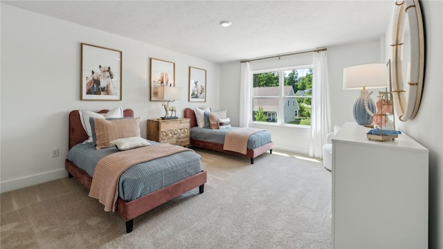 bedroom with light carpet, a textured ceiling, and baseboards