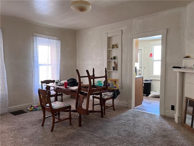 dining space with carpet, ornamental molding, and a textured wall