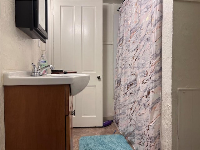 bathroom with tile patterned flooring, a textured wall, vanity, and a shower with shower curtain