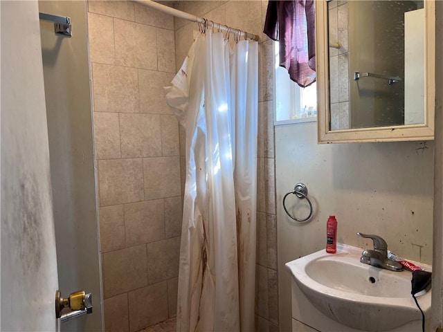 bathroom with a tile shower and vanity