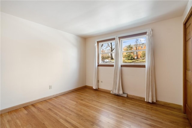 spare room featuring light wood-type flooring and baseboards