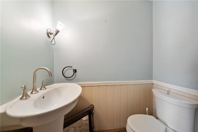 bathroom featuring wainscoting, a sink, and toilet