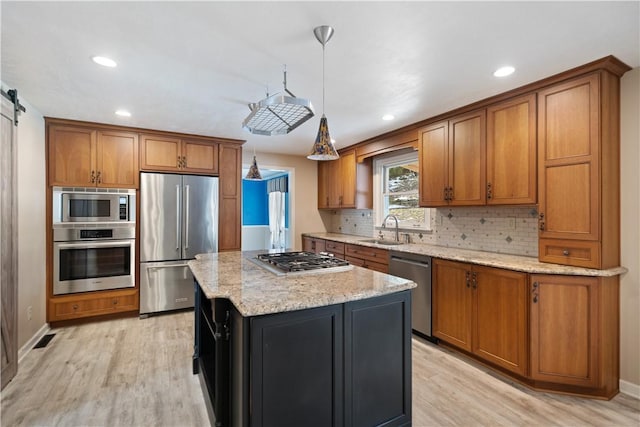 kitchen featuring brown cabinetry, a center island, stainless steel appliances, and decorative light fixtures