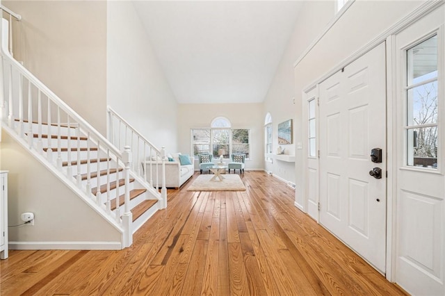 foyer featuring hardwood / wood-style flooring, baseboards, a high ceiling, and stairway