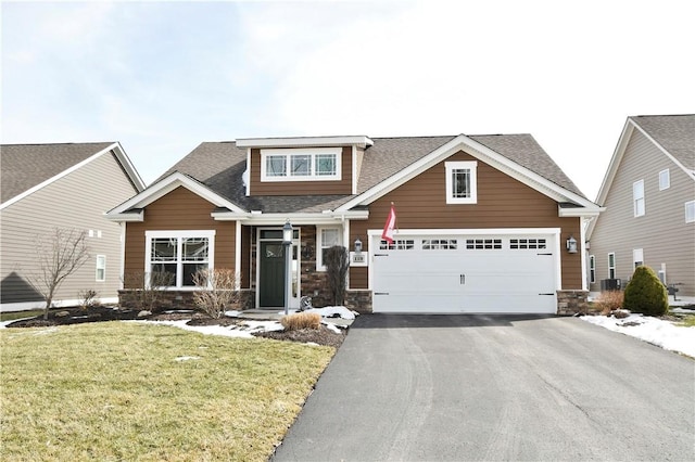 craftsman inspired home with driveway, stone siding, roof with shingles, and a front yard