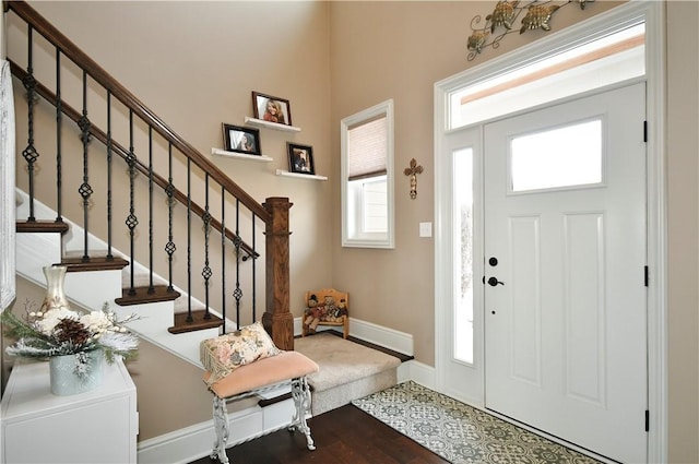 entryway featuring wood finished floors, baseboards, and stairs