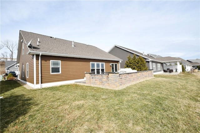 back of property featuring a shingled roof, a lawn, and a patio