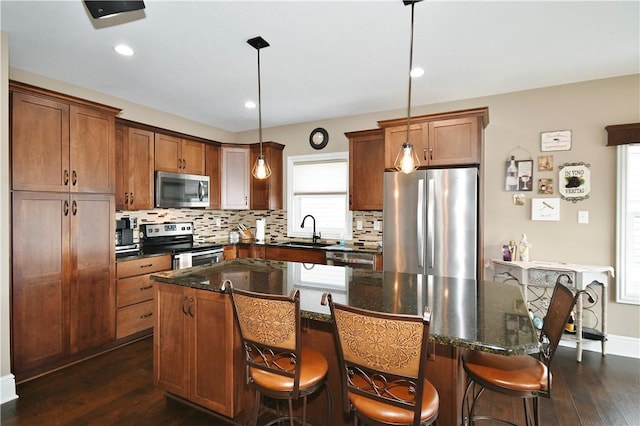 kitchen featuring hanging light fixtures, brown cabinetry, stainless steel appliances, and a center island