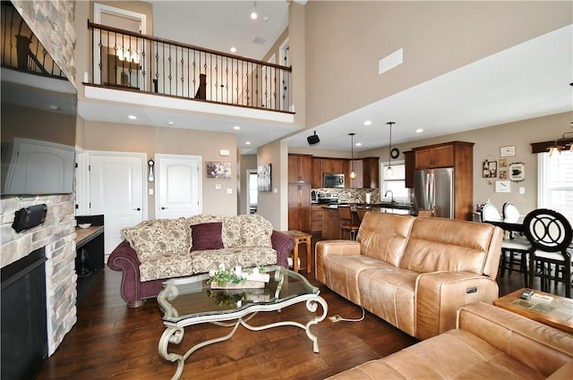 living room with a stone fireplace, recessed lighting, a high ceiling, visible vents, and dark wood-style floors