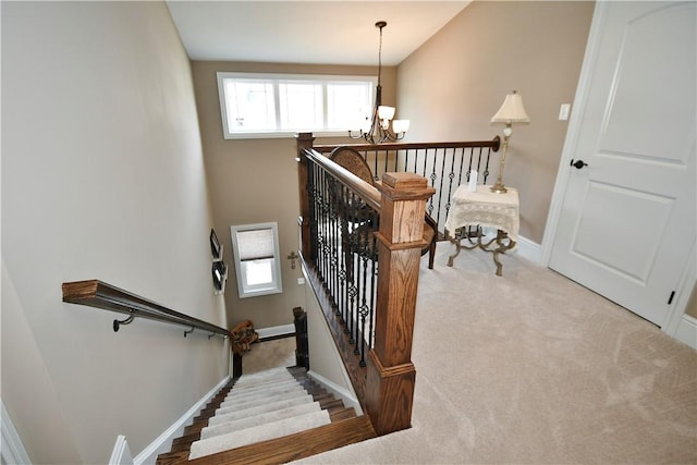 stairway with baseboards, carpet, and a notable chandelier