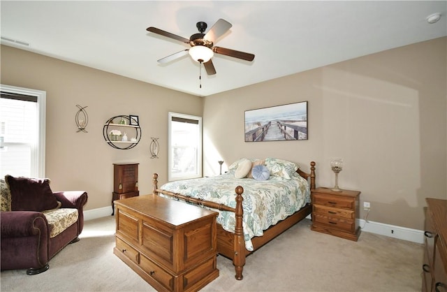 bedroom with light carpet, a ceiling fan, visible vents, and baseboards