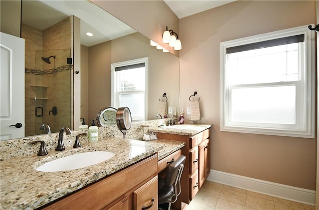 bathroom featuring tile patterned flooring, a sink, a shower stall, and baseboards