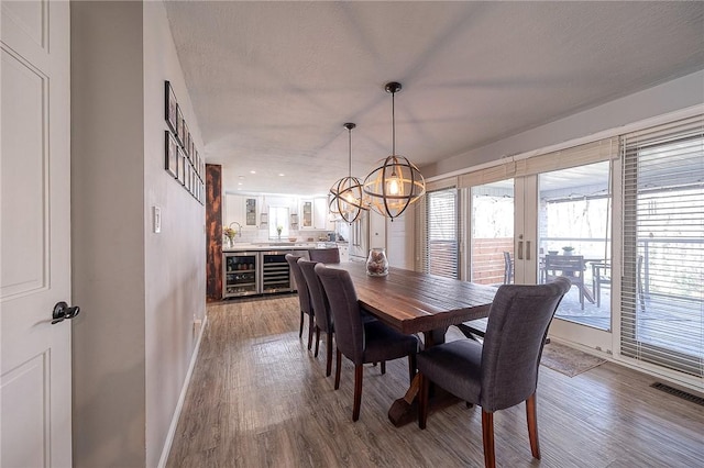 dining room with a textured ceiling, wood finished floors, visible vents, and baseboards