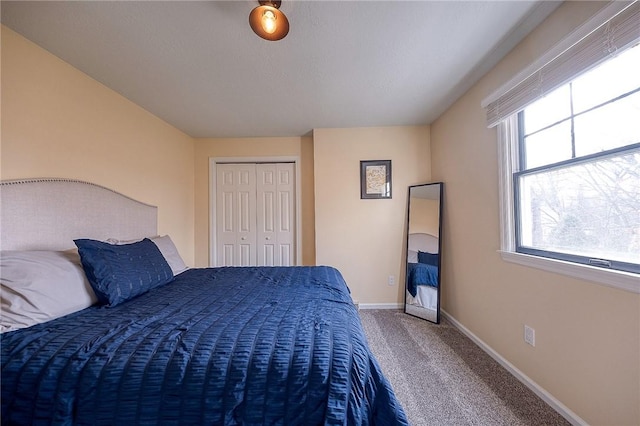 carpeted bedroom with a closet and baseboards